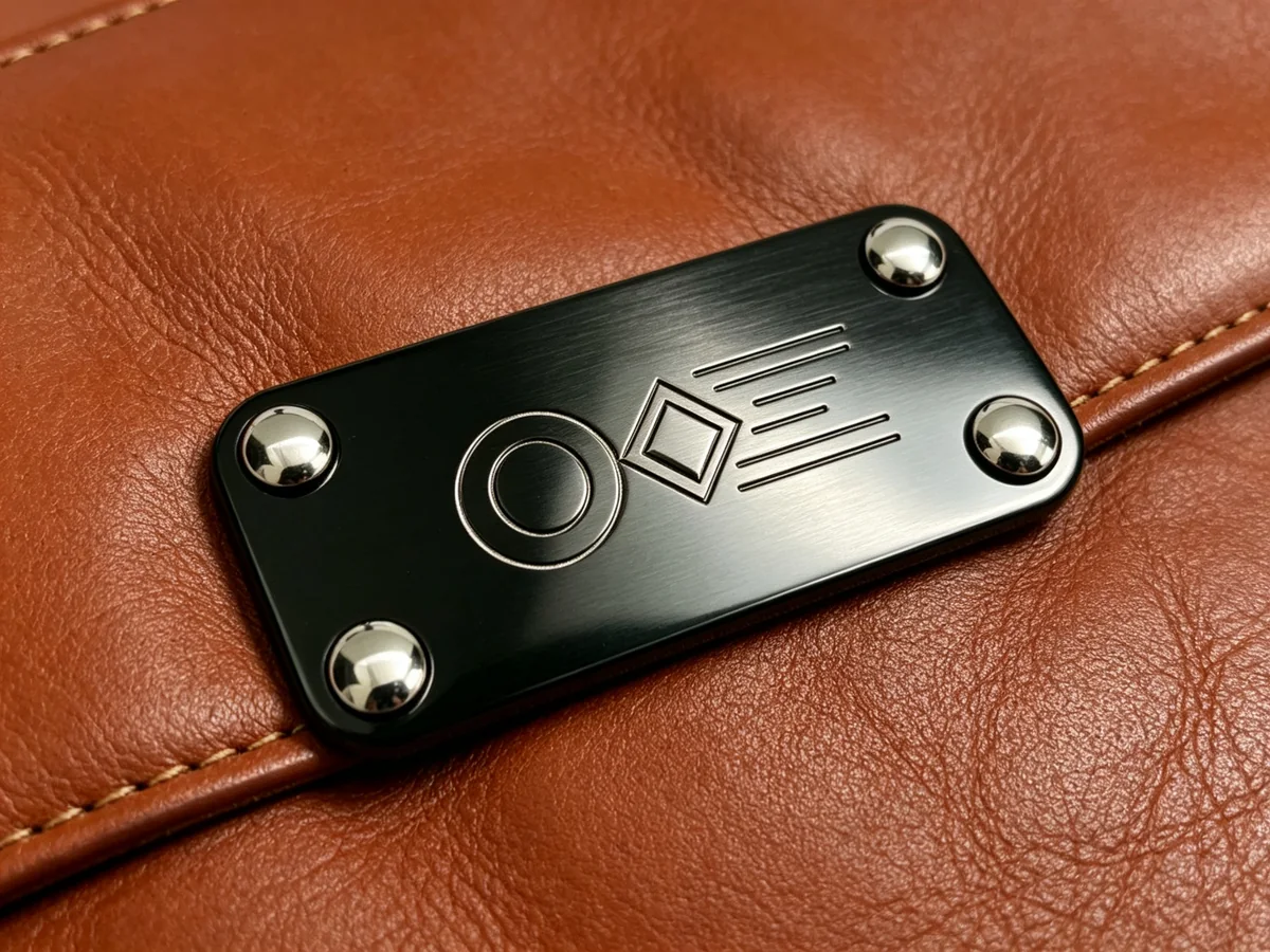 Brushed metal brand plate fixed to brown leather